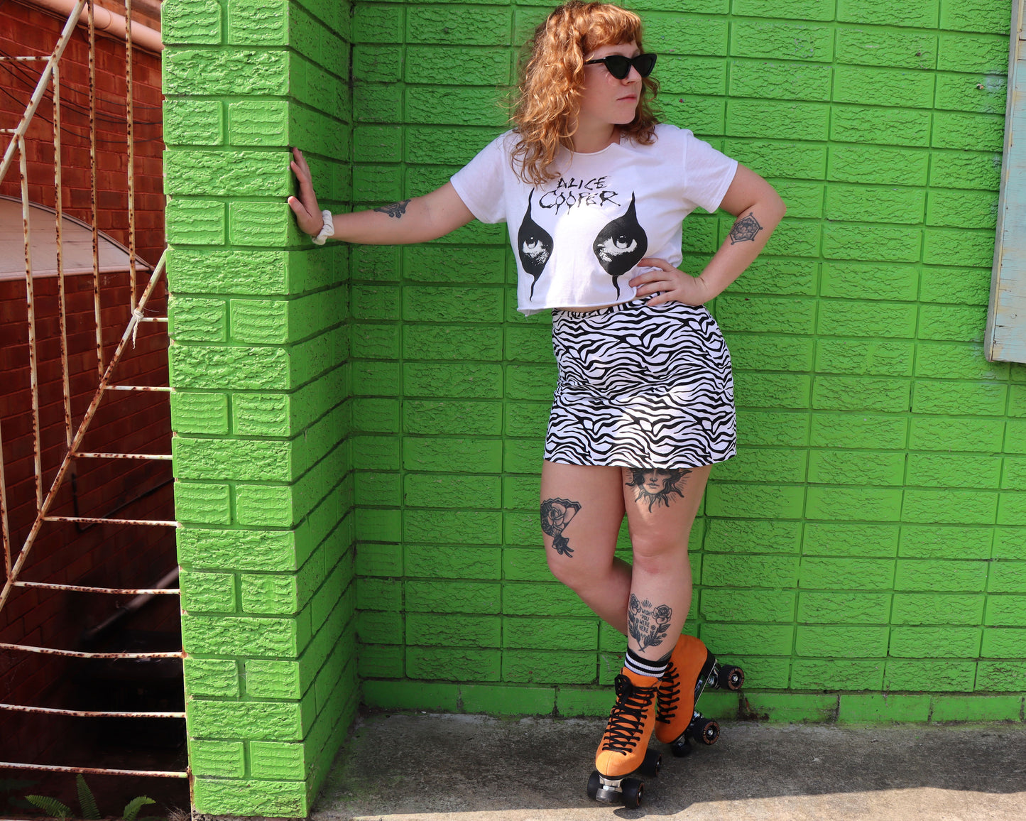 Ginger roller skater wearing Orange Chuffed Roller Skates with green wall