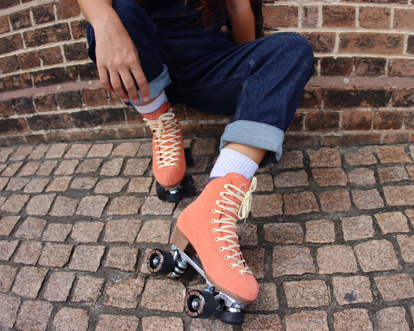 Chuffed Skates peach pink roller skates on brick floor